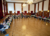 Totale auf ein Sitzungszimmer mit in U-Form gruppierten Tischen, an denen die Konferenzteilnehmer:innen sitzen.