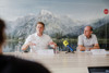 Landesrat Stefan Kaineder und DI Christian Kneidinger sitzen nebeneinander an einem Konferenztisch, im Hintergrund großes Foto mit See und Gebirge