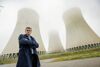 Umwelt-Landesrat Stefan Kaineder stehend vor einem Atomkraftwerk.