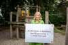 Landeshauptmann-Stellvertreterin Christine Haberlander auf einem Spielplatz mit einem Plakat mit dem Text: „67.265 Kinder in Betreuung – Kinderland Nr.1 nimmt Fahrt auf!“