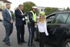 Puckings Bürgermeister Thomas Altof, LR Günther Steinkellner, Polizistin Antonietta Hintringer und eine Schülerin stehen auf einer Straße vor der Fahrerseite eines Autos bei der Apfel-Zitrone Aktion.