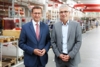 Wirtschafts-Landesrat Markus Achleitner mit Harald Schröpf, CEO der TGW Logistics Group stehen nebeneinander in einem Lagerraum der Fa. TGW Logistics Group, Marchtrenk.