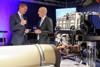 v.l.: Wirtschafts- und Energie-Landesrat Markus Achleitner und Wirtschaftsminister Martin Kocher stehen nebeneinander in einer Halle; rechts von Ihnen ist ein Motor zu sehen.