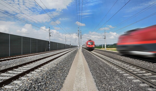Blick auf die Gleise der Westbahnstrecke mit zwei fahrenden Zügen  