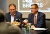 Ing. Mag. Wolfgang Mayer und Landesrat Markus Achleitner sitzen nebeneinander an einem Konferenztisch, vor ihnen Mikrofone und ein Körbchen mit Gebäck