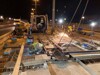 Bauarbeiter bei Arbeiten an einer Schienenanlage auf einer Brücke bei Nacht