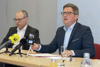 Mag. Dietmar Krenmayr, MA, und Landesrat Mag. Michael Lindner sitzen nebeneinander an einem Konferenztisch mit Mikrofonen