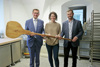 Wirtschafts- und Raumordnungs-Landesrat Markus Achleitner steht mit Christina und Gerhard Helmberger in einer Backstube; gemeinsam halten sie einen großen Brotschieber in ihren Händen. 
