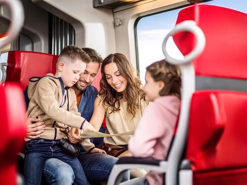 Junge Familie mit zwei Kindern sitzt in einem Zugabteil 