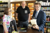 Judith Ringer, Bernd Fischer und Landesrat Markus Achleitner stehen um einen Tisch mit Scanner in einem Lebensmittelverkaufsraum