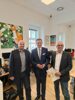 Wolfgang Eibner, Landesrat Markus Achleitner und Nikolaus Dürk stehen nebeneinander in einem Büroraum