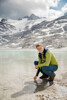 Landesrat Stefan Kaineder greift ins Wasser eines Eissees in felsiger Hochgebirgslandschaft