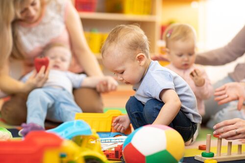 Kleinkinder und Betreuerinnen spielen mit Spielzeug