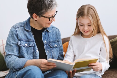 Eine Frau und ein Kind sitzen nebeneinander und lesen in einem Buch