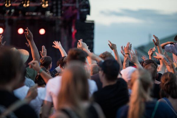 Junge Festivalbesucher tanzen vor einer Konzertbühne