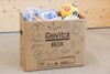 Schachtel aus Karton mit Beschriftung ReVital-Box beinhaltet verschiedene Gegenstände wie Geschirr, Spielball, Dekorfliese