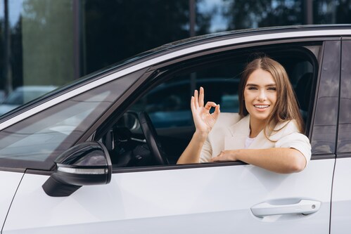 Eine Frau deutet ok aus dem Autofenster 