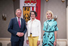 Landeshauptmann Mag. Thomas Stelzer, Dr.in Christine Haiden und Mag.a Simone Lindinger stehen nebeneinander in einem barocken Raum, im Hintergrund Oberösterreich-Fahne 