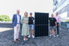Fünf Personen, darunter Landeshauptmann-Stellvertreterin Mag.a Christine Haberlander, stehen nebeneinander auf einem geschotterten Flachdach, zwei Jugendliche halten ein großes Solarpaneel