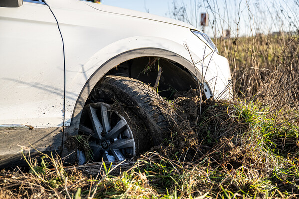 Ein Auto dessen Vorderreifen in einem Feld fest steckt.